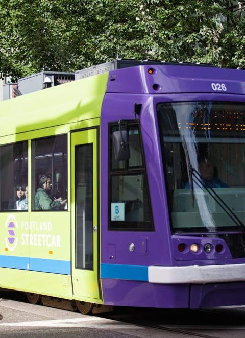 a green and purple train on a city street