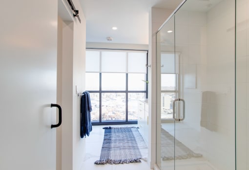 a bathroom with a glass shower and a blue rug