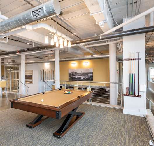Industrial-style game room at Converse Mill Lofts with a pool table and a bar.