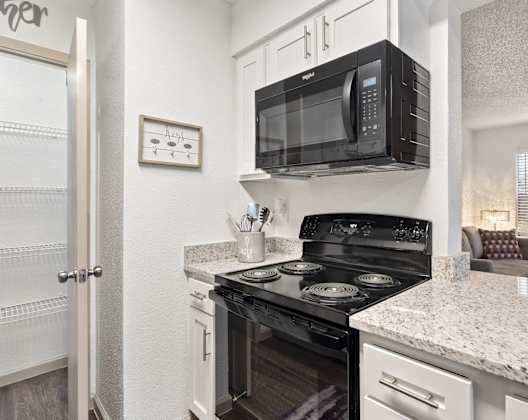 A black microwave is mounted above a black stove in a kitchen.