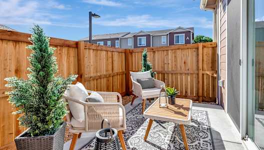 Patio with two chairs and a table and a fence