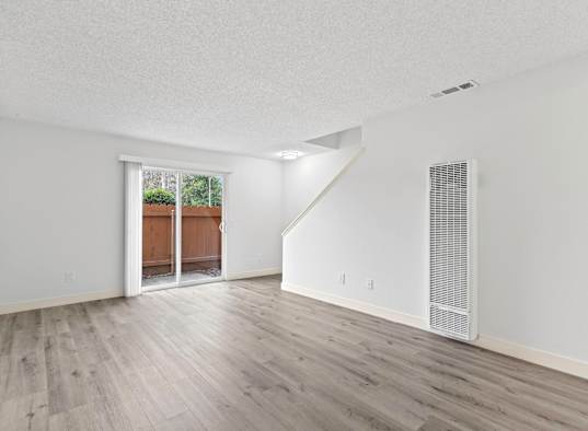 A room with a white ceiling, wooden floors, and a window with a view of a backyard. at Stony Creek Apartments, Santa Rosa, 95401