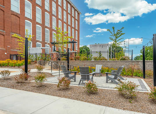 Patio with chairs and a table in front of Converse Mill Lofts apartments.