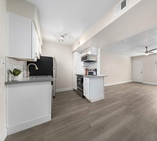 A spacious kitchen with white cabinets and a black fridge.