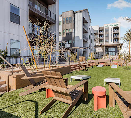 A sunny day at a modern apartment complex with a grassy courtyard and wooden furniture.
