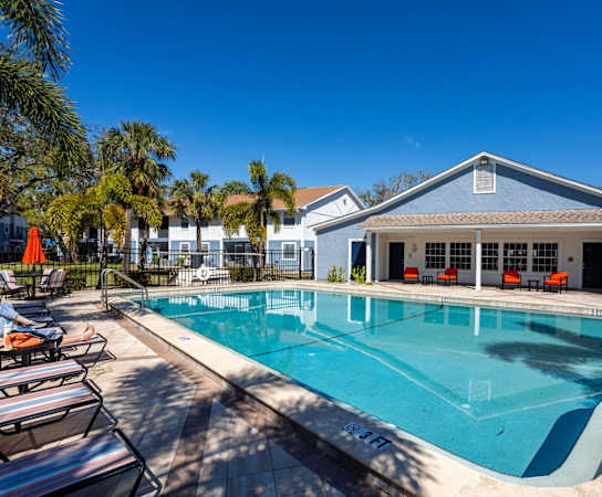 A large swimming pool with lounge chairs and a house in the background.