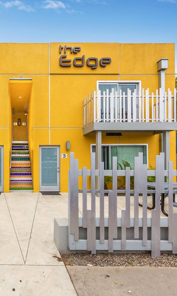 The Edge building has a yellow facade and white fences.