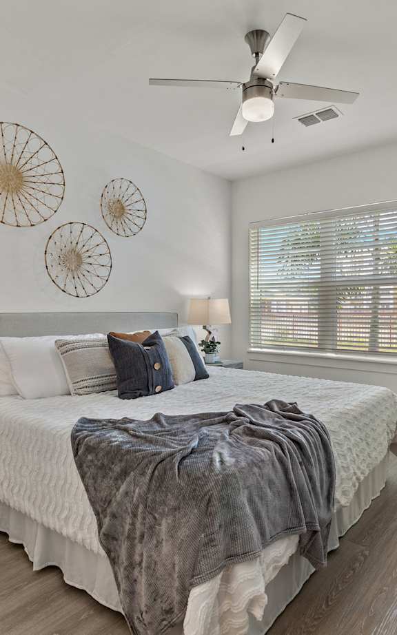A bedroom with a large bed and a ceiling fan.