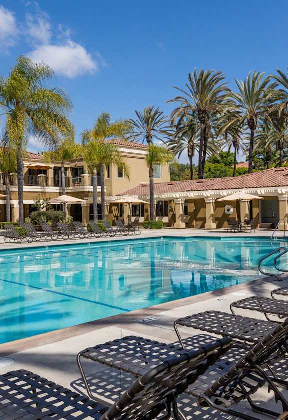 a swimming pool with lounge chairs and umbrellas in front of a hotel