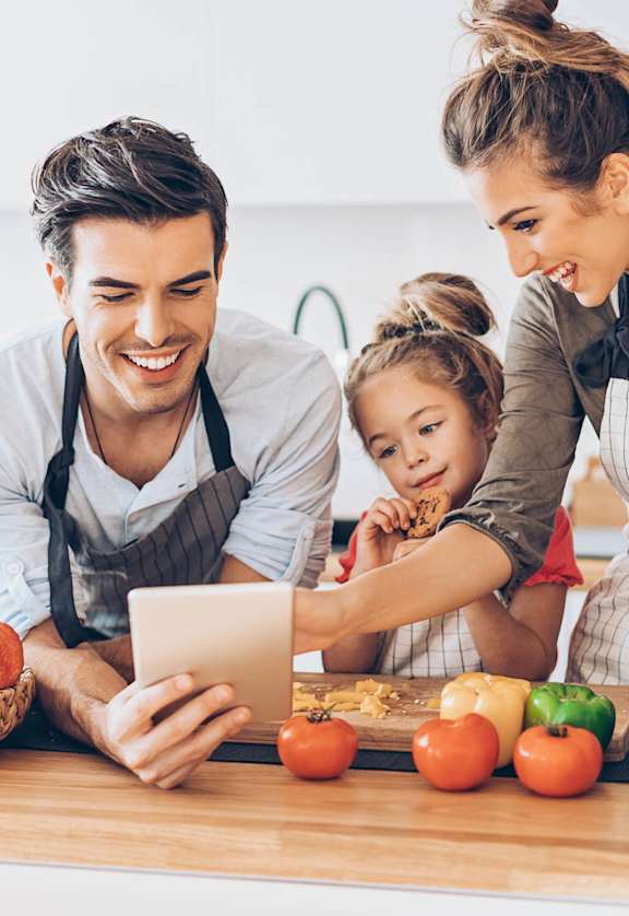 A family of three is preparing a meal together in the kitchen.