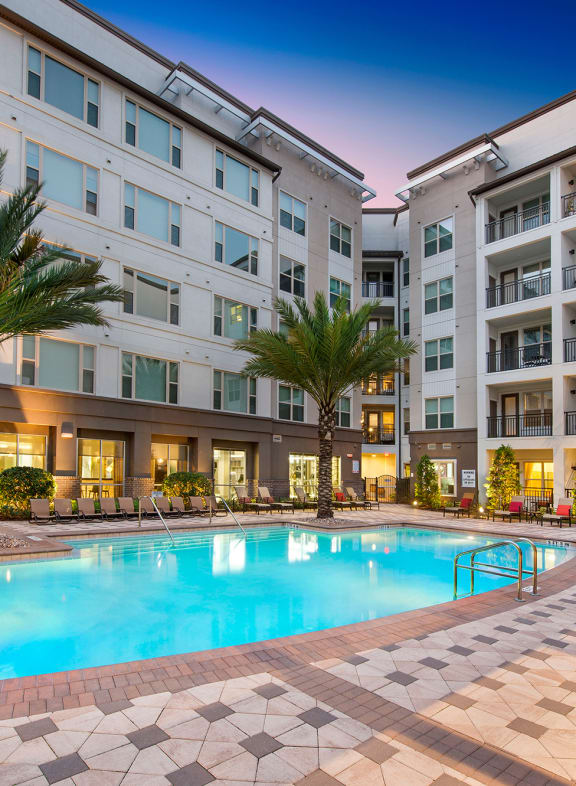 a pool area with palm trees and a building in the background at The Rialto, Orlando, 32819