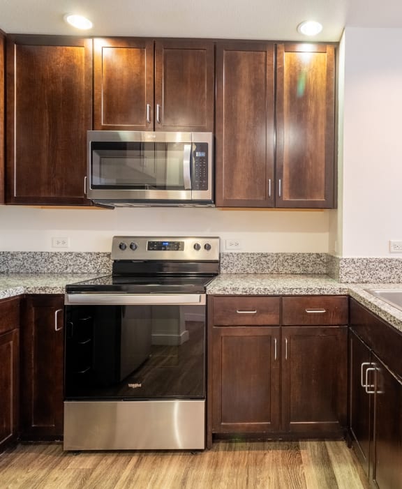 a kitchen with wooden cabinets and granite counter tops and stainless steel appliances at Strata at Mission Bay, San Francisco, CA, 94158