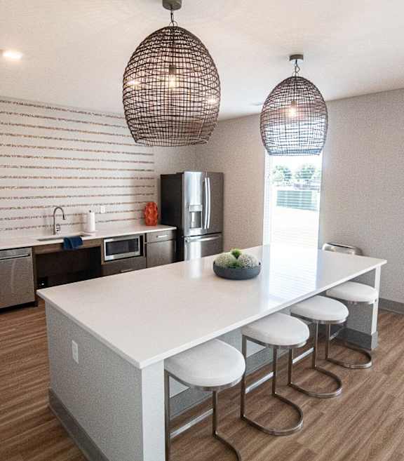 A kitchen with a white island and bar stools. at Centennial Crossing, Waukee, 50263