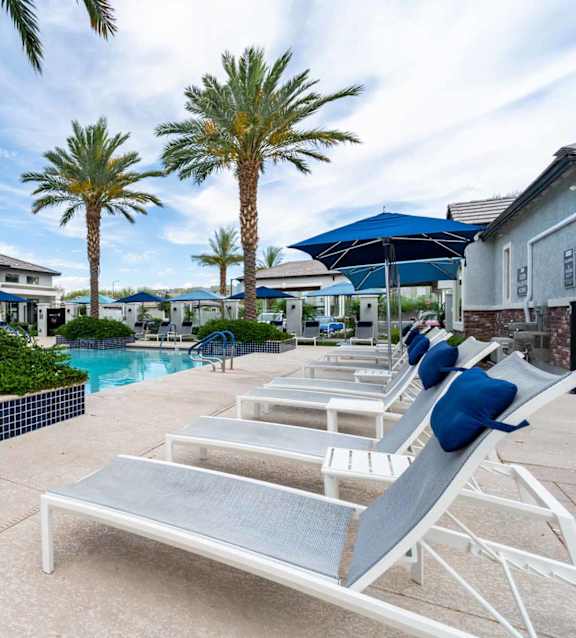 A poolside area with sun loungers and palm trees. at Vistoria At Stadium Apartments, Glendale, Arizona