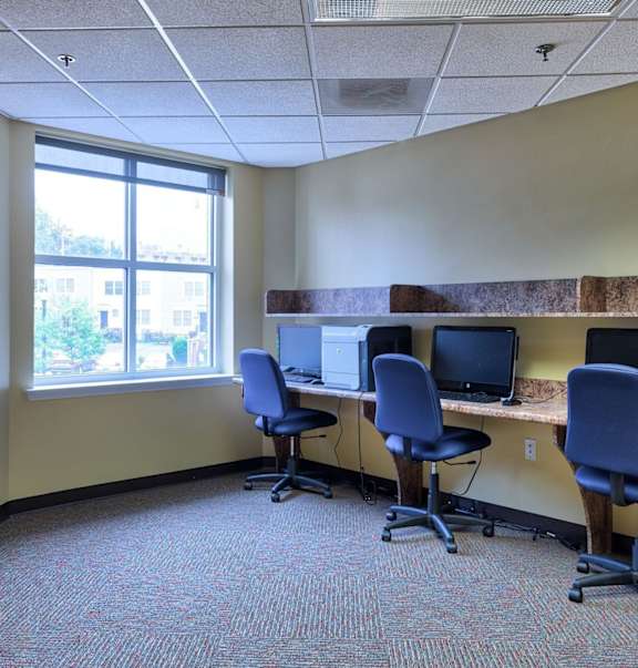 a large office with three desks with computers and chairs