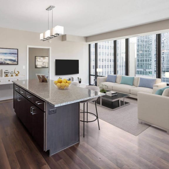 The living room with a couch, plush chairs, coffee table, decorations, a TV, with floor to ceiling windows showing the Minneapolis surrounding skyscrapers, and a view of the dining room and the kitchen at NIC on 5th Apartments. 