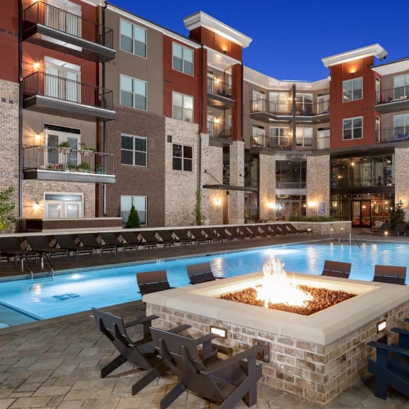 an outdoor pool with a fire pit in front of an apartment building