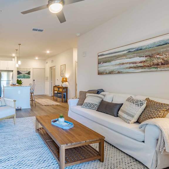 A living room with a white couch and a painting on the wall.