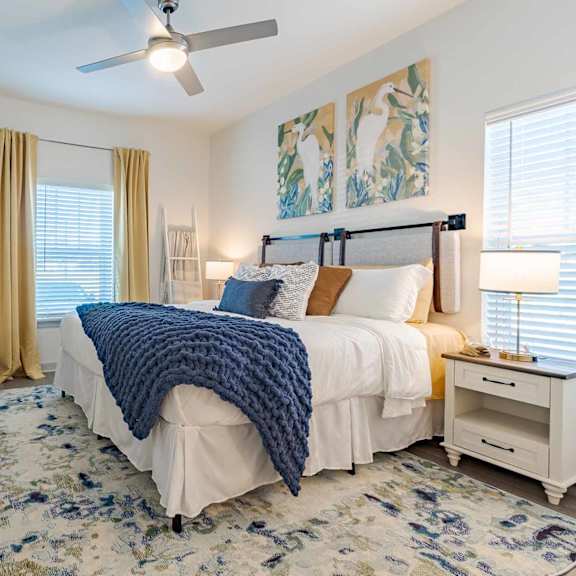 A bedroom with a bed, nightstand, and a ceiling fan.
