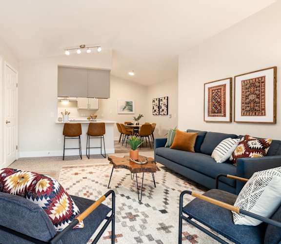 a living room with couches and chairs and a kitchen with a table and chairs