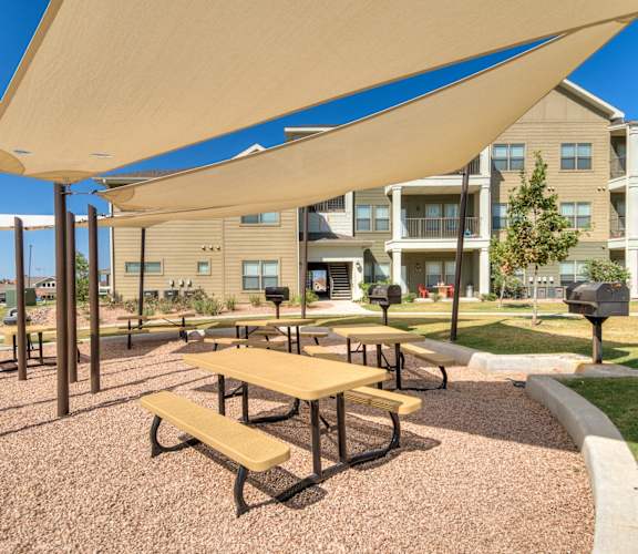 a picnic area with benches and tables in front of an apartment building