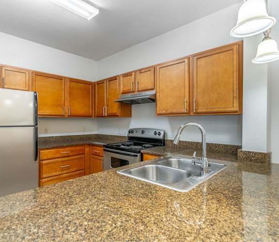 a kitchen with granite counter tops and a stainless steel refrigerator