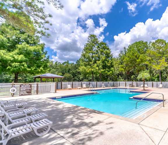 a swimming pool with chairs and a fence around it