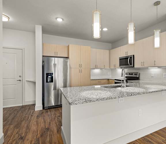 A kitchen with a granite countertop and stainless steel appliances.