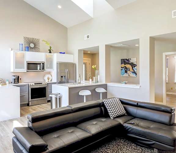 A black leather couch sits in a modern kitchen and living room at Sedgefield Square Apartments, North Carolina, 27407