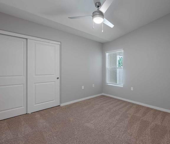 A room with a ceiling fan and two doors.