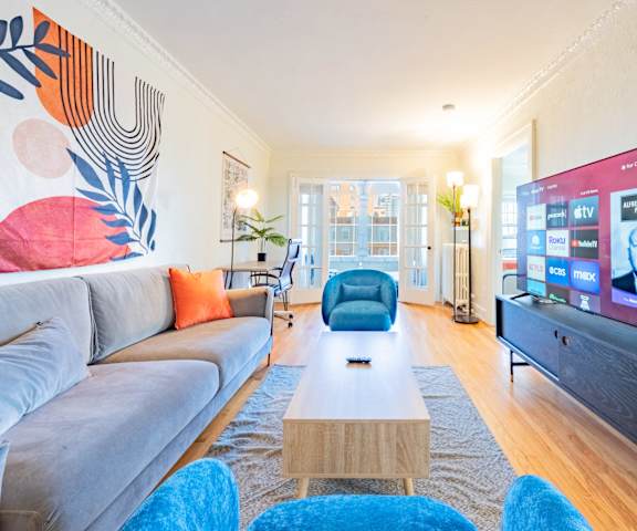 A modern living room with a grey couch, a wooden coffee table, and a large flat screen TV.