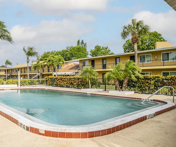 a swimming pool in front of a hotel with palm trees
