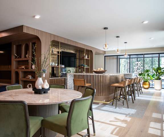 A modern dining room with a round table and green chairs.