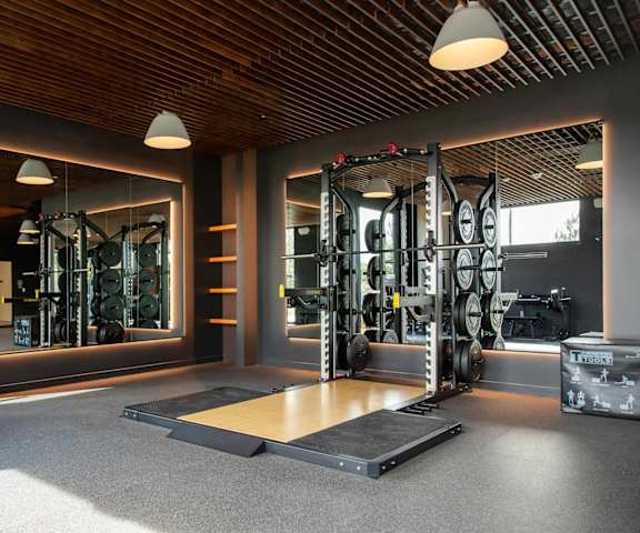 A gym with a variety of equipment including a squat rack, bench, and weights.