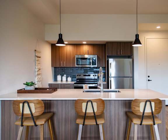 A kitchen with a white countertop and wooden chairs.
