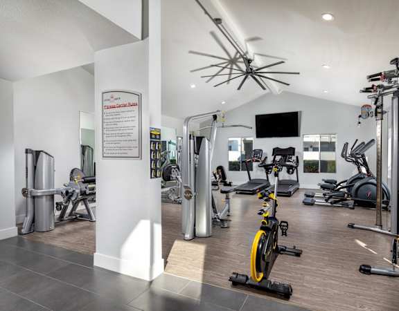 A gym with a variety of equipment including treadmills, weights, and exercise bikes.