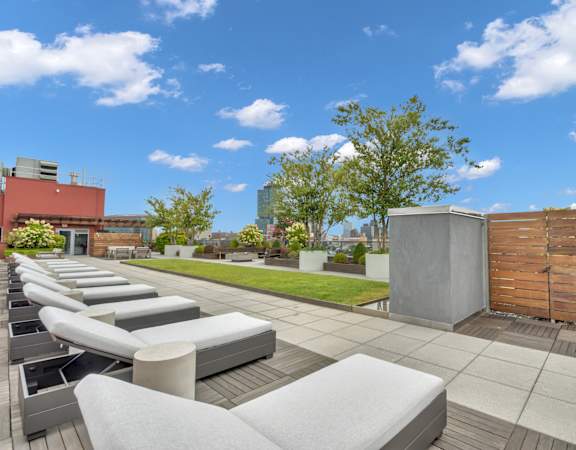 a rooftop patio with white couches and a grassy area and a wooden fence