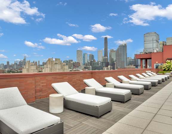 a terrace with white lounge chairs and a view of the city