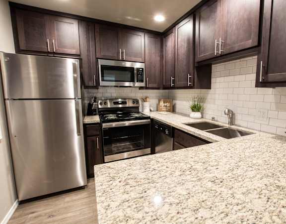 furnished kitchen with marble counter tops and stainless steel appliances