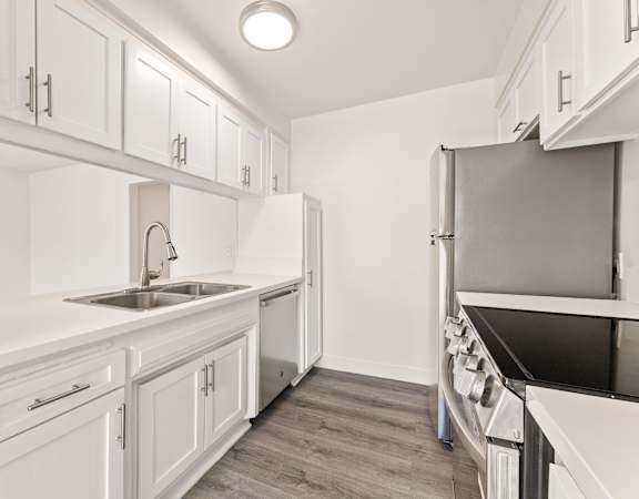 A kitchen with white cabinets and a sink.