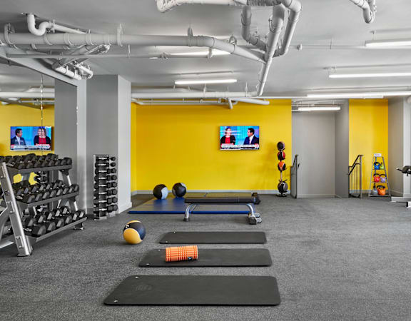 A gym with a variety of equipment including weights, a bench press, and a treadmill.
