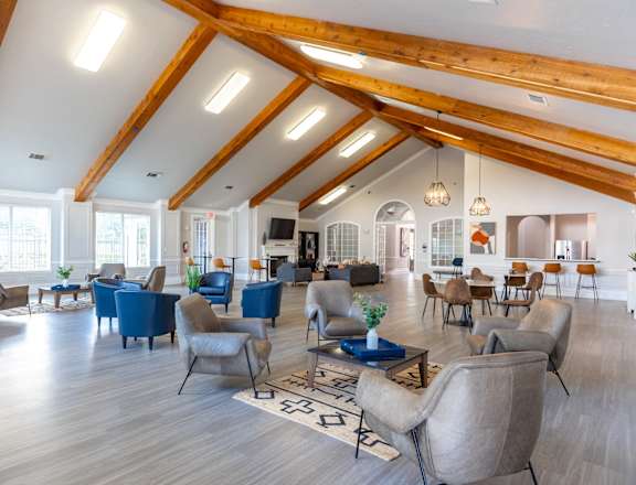 A spacious living room with wooden beams and blue chairs.