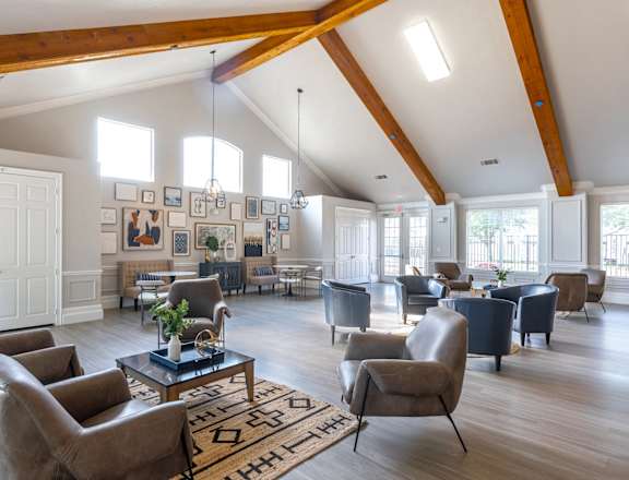A living room with a high ceiling and wooden beams.