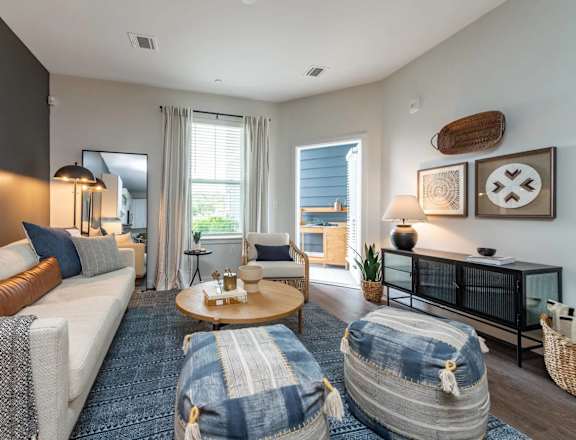 A living room with a white couch, a coffee table, and a large window.
