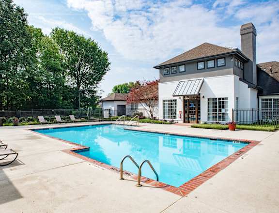 a swimming pool with lounge chairs and a building in the background