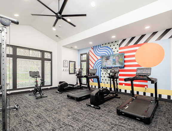 a fitness room with treadmills and weights and a large window