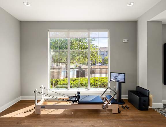 A room with a wooden floor and a row of windows.