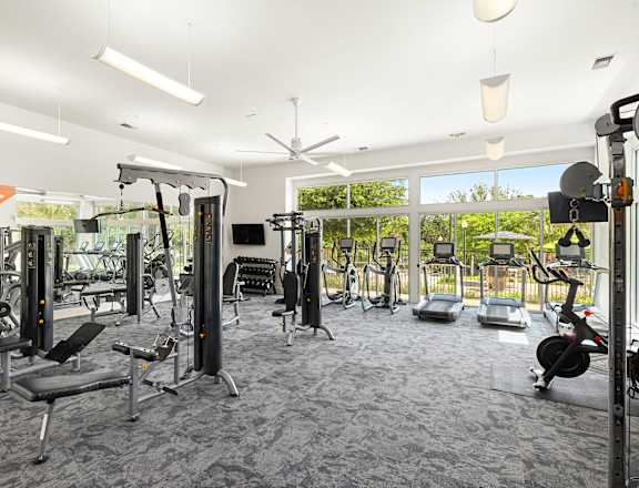 a gym with weights and cardio equipment in a building with large windows
