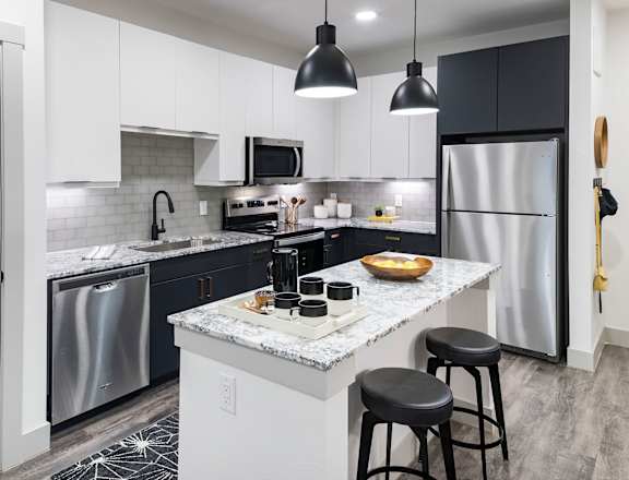 A kitchen with a white island and black stools.