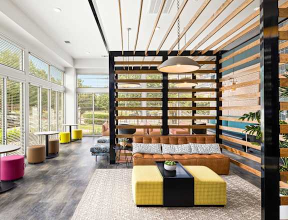 a lounge area with a couch and tables in a room with large windows